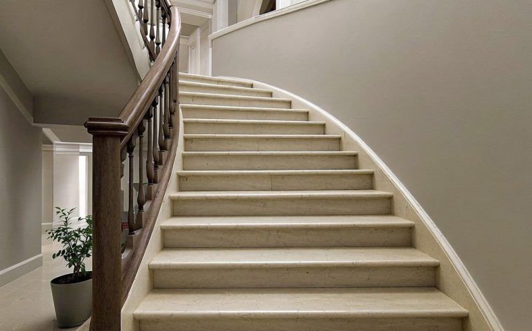 Treppenhausreinigung Eine geschwungene Treppe mit hellen Stufen und einemHolzgeländer in einem modernen Raum.